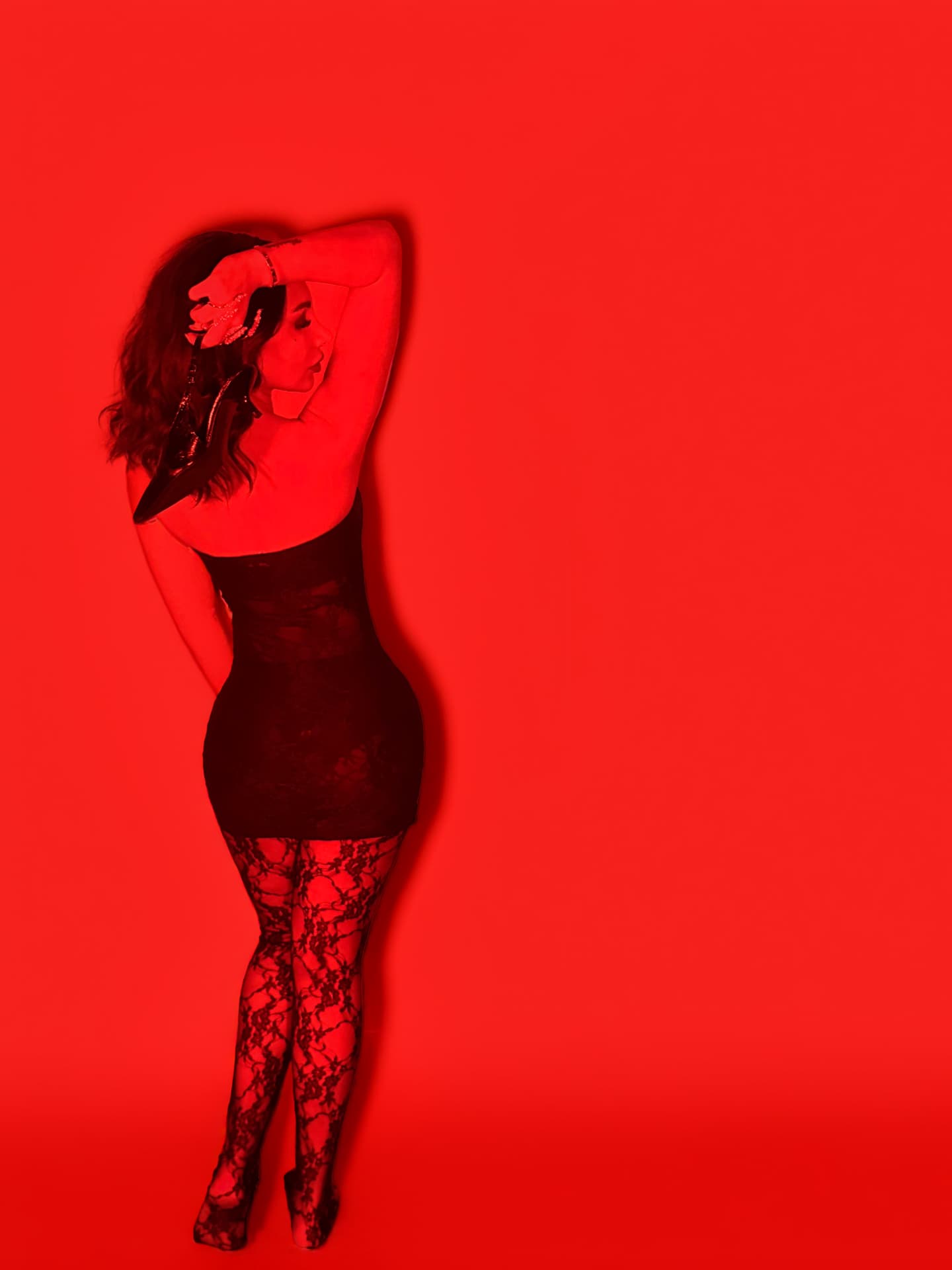 Jada Davino full length in black lace against a scarlet wall