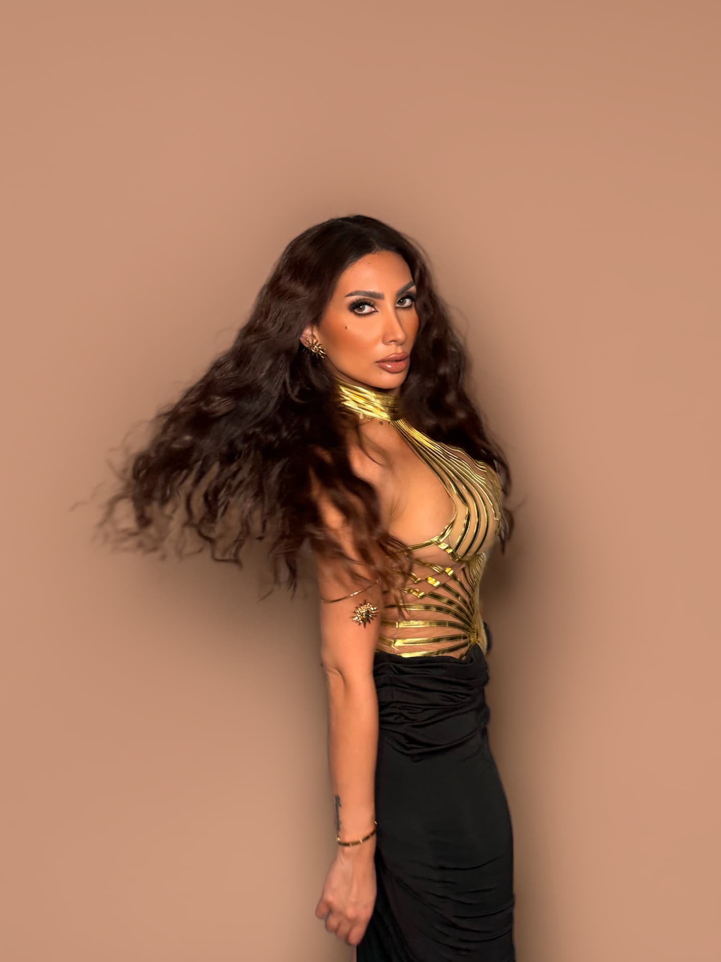 Jada Davino in a gold harness bodice, hair in motion