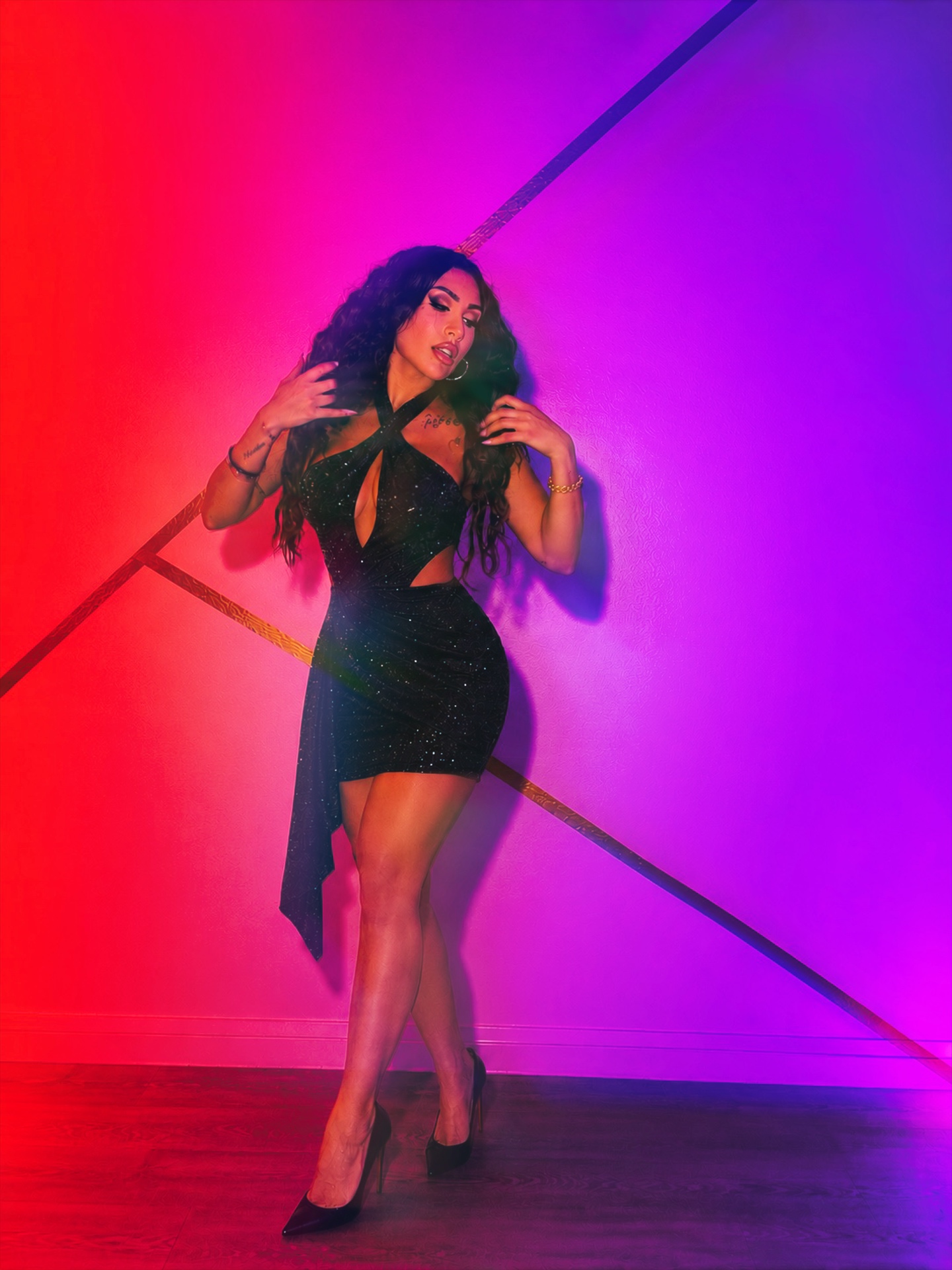 Jada Davino in a sequinned black dress against red and violet light